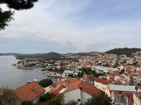 Kırmızı çatılı binaları ve sakin deniz manzaralı manzaralı bir sahil kasabası..