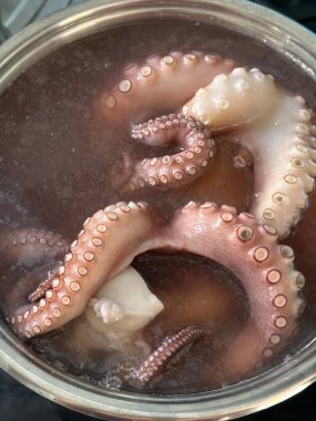 Suya batırılmış ahtapot dokunaçlarının yakın çekimi dokuyu ve detayları gösteriyor. Ahtapot çorbası..