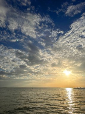 Gün batımında sakin bir deniz manzarası Bulutlu bir gökyüzü ve sakin sularla.