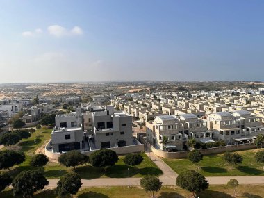 Üniformalı evleri, yeşil alanları ve temiz gökyüzü olan modern bir banliyö manzarası..