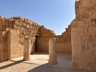 Açık mavi gökyüzünün altında sütunları olan antik taş kalıntıları.