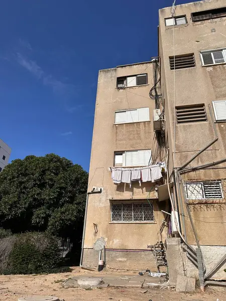 Açık mavi gökyüzünün altında kirli çamaşırları asılı yıpranmış bir apartman..