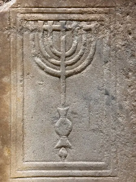 Yedi dallı bir şamdan olan menoranın yer aldığı antik bir taş oyması Yahudi mirasını ve geleneğini sembolize ediyor. Karmaşık tasarım tarihi sanatları sergiliyor.