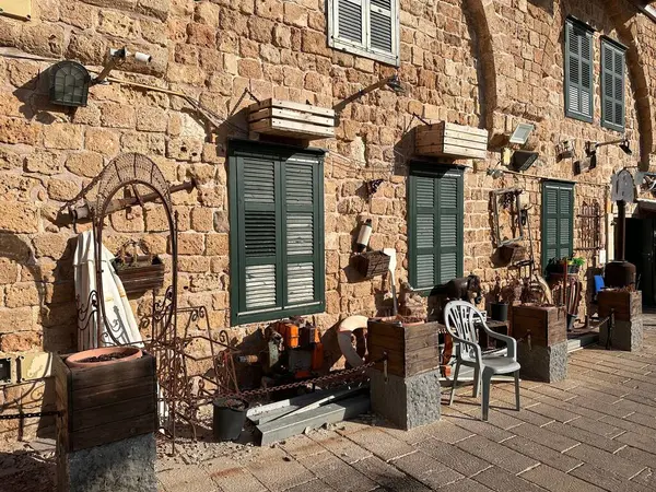 Ahşap ekiciler ve çeşitli dekoratif malzemelerle süslenmiş yeşil pencere panjurlu taştan bir duvar. Sahne, büyüleyici bir dış mekan sunan doku ve renklerin karışımını içeriyor..