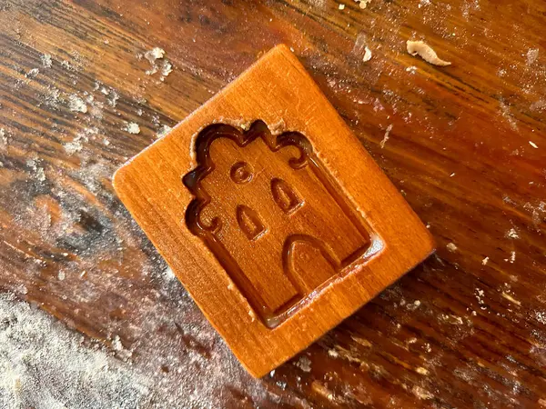 Kemerli girişi ve dekoratif unsurları olan ahşap bir binanın oyulmuş bir tasarımını içeren ahşap bir pul..