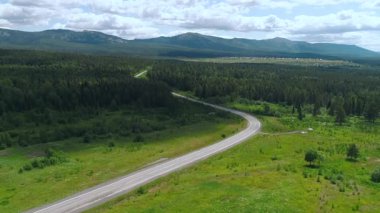Yazın dağlarda dağlarla birlikte yolun havadan görünüşü. Güzel yeşil orman ve yol.