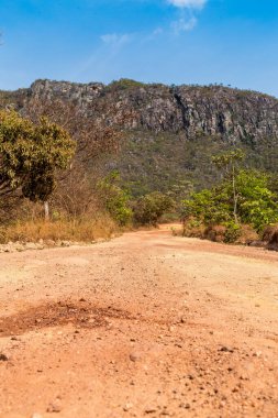 Arka planda dağlar olan çamurlu bir yol.