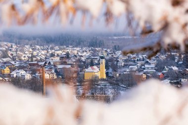 Karlı Köy Manzarası Şekerli Dallar Tarafından Çerçevelendi. Çatıları ve ağaç dalları arasından görülen sarı bir kilise kulesi olan kış kasabası manzarası. Bavyera, Almanya, Frauenau