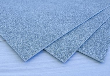 Several silver glitter foam sheets stacked together on white wooden surface. Perfect for craft projects, DIY, decor and creative art ideas.