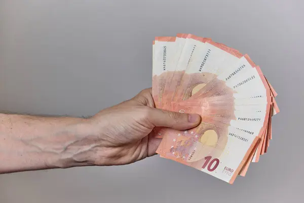 Temiz ve nötr bir arkaplanda avroya ait çeşitli banknotları tutan bir insan elinin yakın çekimi. Finans, maaş, yatırım, tasarruf veya ödeme kavramı.