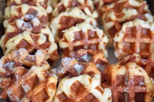 Büfe tepsisine istiflenmiş pudra şekerli altın kahverengi gözlemeler..