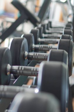 Spor salonunda arka arkaya dizilmiş bir çift dambıl. Egzersiz ekipmanları.