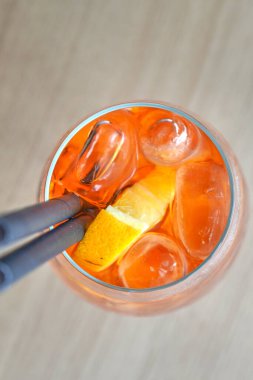 Bardakta buz küpü tutan maşayla Aperol sprey kokteylini yakından izleyin.