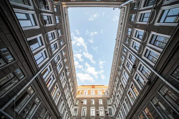 Tarihi tuğla bir avluda, dikdörtgen bir deliğin içinden yukarıya bakıyorum.