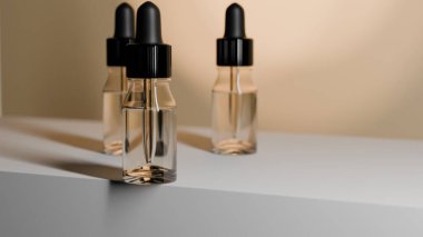 Beyaz yüzeyde siyah kapaklı iki temiz cam damlacık şişesi.