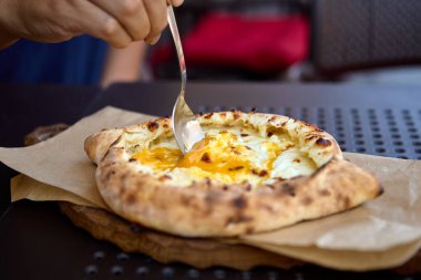 Gürcistan khachapuri 'sinden eritilmiş peynirle doldurulmuş ve yumurtalı bir dilim servis ediliyor.