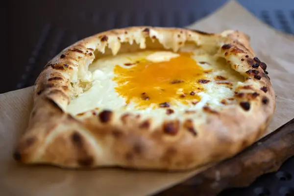 Taze pişmiş Gürcistan khachapuri 'si erimiş peynirle doldurulmuş ve üzerine de güneşli bir yumurta konmuş.