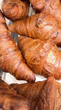 Sarı kahverengi kruvasanların yakın çekim videosu, yumuşak katmanlı, taze pişmiş hamur işi Fransız mutfağını, kahvaltısını ve lezzetli pastane yemeklerini simgeliyor.