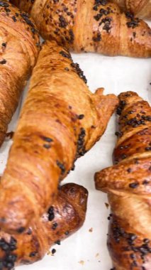 Sarı kahverengi kruvasanların yakın çekim videosu, yumuşak katmanlı, taze pişmiş hamur işi Fransız mutfağını, kahvaltısını ve lezzetli pastane yemeklerini simgeliyor.