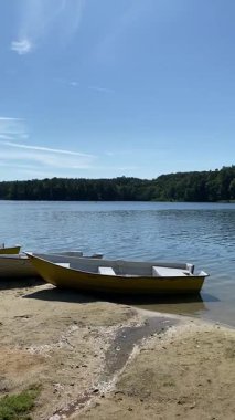 Uzakta ormanı olan sakin bir gölün kumlu sahiline yerleştirilmiş küçük tekneler.