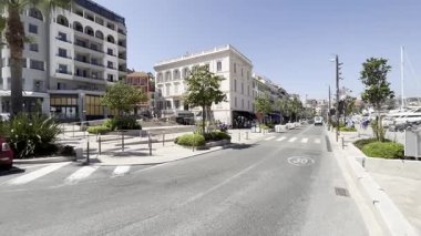 Cannes, Fransa - 24 Mayıs 2023: Cannes Film Festivali sırasında liman yakınında binalar ve palmiye ağaçları olan cadde