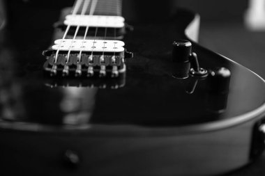 Elektro gitar gövdesinin tek renkli görüntüsü briç, teller ve kontrol düğmelerini gösteriyor. Ayrıntılı doku işçiliği ve rock müzik atmosferini vurguluyor.