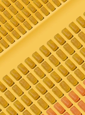 Sıcak sarı bir yüzey boyunca çaprazlama dizilmiş altın jöle şekerlemelerinin yer aldığı sanatsal bir yemek fotoğrafı modern bir minimuma yakın bir şekerlemeden esinlenerek hazırlanmıştır..