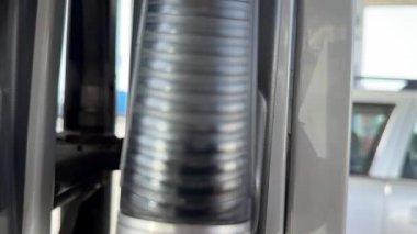 Benzin istasyonunda, endüstriyel tasarım odaklı enerji ve yakıt ikmal ekipmanlarını vurgulayan tırtıklı yakıt pompası hortumunun detaylı bir yakın çekimini gösteriyor..