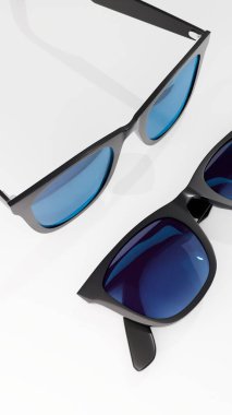 Siyah çerçeveli bir çift şık güneş gözlüğü ve parlak mavi yansıtıcı lensler yüksek kaliteli stüdyo görüntülerinde temiz beyaz bir arkaplanda izole edilmiş..