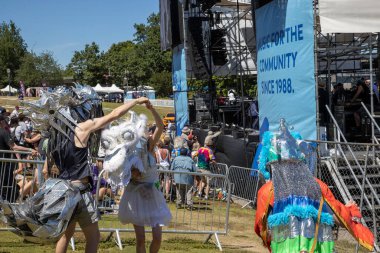 PORTLAND, OR, ABD 5 Temmuz 2025 İnsanlar özenle hazırlanmış yaratık kostümleri içinde ana sahnenin yanında dans ediyorlar Tom McCall Waterfront Park 'taki Willamette Nehri kıyısında