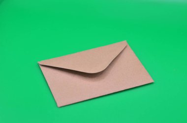 Yeşil arka planda kahverengi bir zarfın yakın plan fotoğrafı.