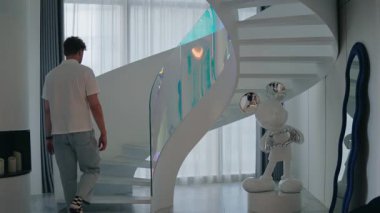 Modern Beyaz Sarmal Merdivenler 'e tırmanan adam, gündelik giysiler içindeki genç adam şık iç mekanlarda beyaz sarmal merdivenlere tırmanır heykel ve kıvrımlı ayna ile, yumuşak gün ışığı boşluğu doldurur.