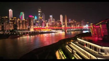 Hava aracı görüntüsü Chongqings 'i gösteriyor. Geceleri gökyüzü aydınlanıyordu. Nehir üzerinde canlı yansımalar ve şehrin kalbinde etkileyici modern mimari yansımalar vardı.