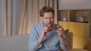 Genç adam, oturma odasındaki kanepede rahat bir şekilde otururken kızarmış tavuğun tadını çıkarıyor. Yavaş çekim zevki sırasında gözlerini kapıyor.