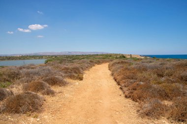 The path between sea and lagoon in the Vendicari Nature Reserve wildlife oasis, located between Noto and Marzamemi, Sicily, Italy