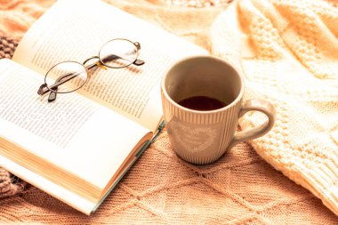 Bir fincan kahve ve kitapla kaplı rahat kazaklar.