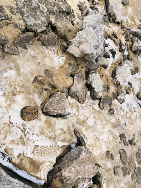 Kayalar, kumlar ve eriyen kirli karlarla dolu doğal bir araziye yakın çekim. Dokuların zıtlığı katı taş, gevşek kum ve solan kar mevsimler ve doğanın saflığı arasındaki geçişi yakalar. Çevre gibi temalar için harika