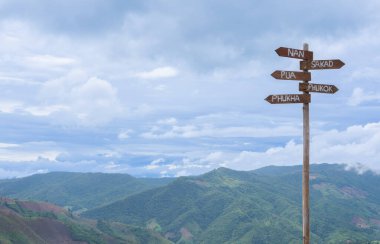 Bereketli bir dağ manzarasının kenarında, Nan, Pua, Phukha, Phukok ve Sakadwhere 'e doğru uzanan yıpranmış bir tabela var..