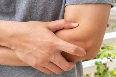 Asyalı bir adam dirseğini içeride acı içinde tutuyor. Kol incinmesi ya da tekrarlanan hareketler ya da ani hareketler gösteriyor. Sağlık ve Tıp Konsepti.