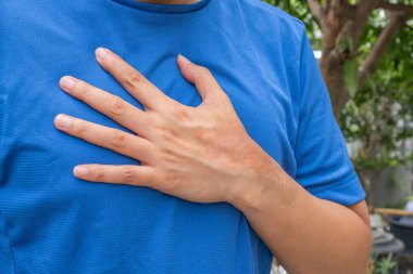 Antrenman sonrası göğüs ağrısı çeken Asyalı bir adam göğsünü endişeyle tutuyor. Jimnastik arka planı. Kalp hastalığı, solunum sorunları ya da kalp riski için uygun. Sağlık ve Tıp Konsepti.