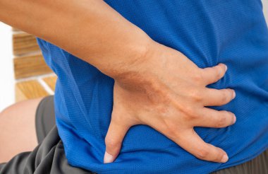 Ev işinden sonra sırtı ağrıyan Asyalı bir adam, rahatsızlık gösteriyor. Ev iç ortamında gerginlik, yaralanma veya kas gevşemesi için tıbbi konsept.