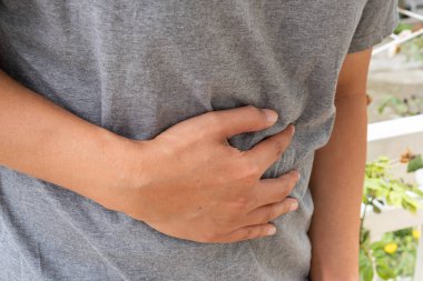 Asyalı bir adam karın ağrısı içinde, şişkinlik, iltihap ya da konutsal ya da tıbbi bir ortamda sindirim sorunları nedeniyle mide ağrısına işaret ediyor. Sağlık ve Tıp Konsepti.
