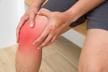 Antrenmandan sonra diz kapağı iltihaplı olan kişi eklem ağrısı ya da gerginlik gösteriyor. Kapalı alan ortamında ahşap bir bankta oturuyordu. Yara iyileştirme reklamları için mükemmel..