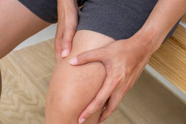 Antrenman sonrası kasları ağrıyan bir adam kas yorgunluğu ya da DOMS gösteriyor. Spor salonundaki ahşap bankta oturuyordu. Fitness sakatlığı için ideal farkındalık.