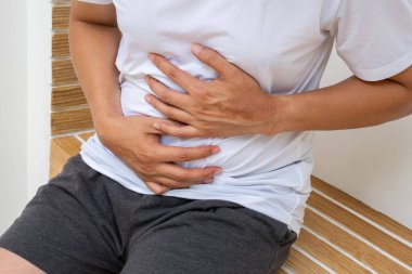 Abdominal rahatsızlık belirtileri gösteriyor, bu da bir evde ya da sağlık temalı reklamlarda görülen şişkinlik ya da iltihaplanmadan kaynaklanan gastrointestinal sıkıntı olduğunu gösteriyor..