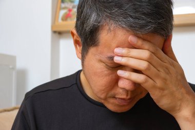 Orta yaşlı Asyalı bir adam. Griple ilgili ağrı, iş stresi ve nörolojik bakım için baş ağrısı çekiyor. Gerçekçi ayarlar tıbbi bağlantıyı geliştirir.