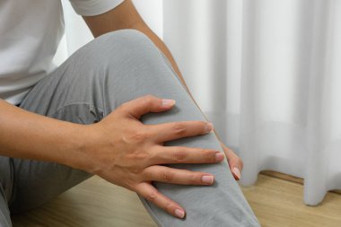 Asyalı bir adam sabah spor sakatlığı, kas gerginliği ve eklem stresi yüzünden bacağını incitiyor. Rehabilitasyon, sağlık ve tıbbi görseller için ideal..