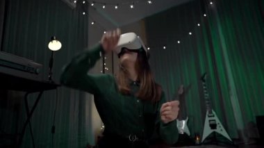 VR kulaklıklı bir kız, giyilebilir VR, ev teknolojisi ve düşük ışıkla bateri çalan neşeli bir kız.