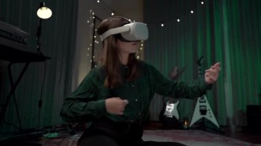 Gitarda çalan genç bir kadın içeride VR kaskı kullanıyor.