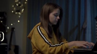 Evde dizüstü bilgisayar kullanmaktan mutlu genç bir kızın portresi.